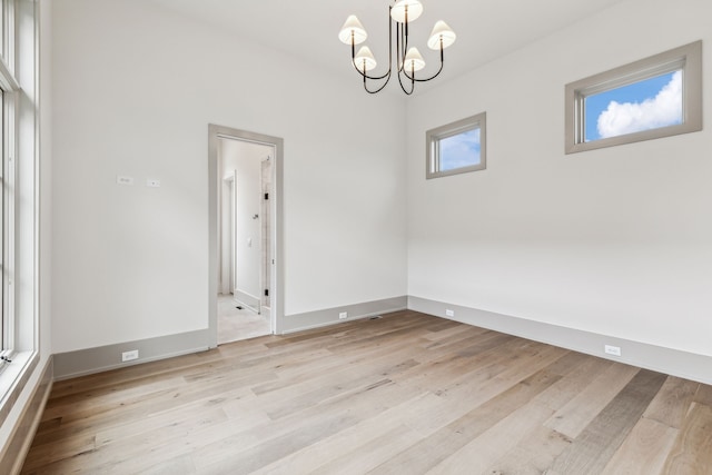 spare room with light hardwood / wood-style flooring and a chandelier