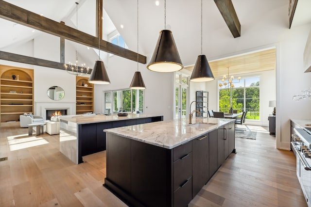 kitchen with pendant lighting, sink, high end stainless steel range, built in features, and a large island