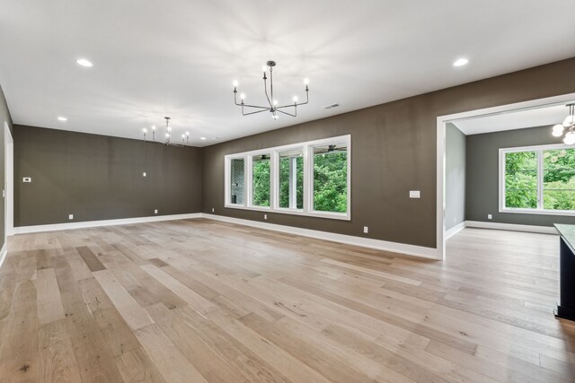 spare room featuring a wealth of natural light, light hardwood / wood-style floors, and a notable chandelier