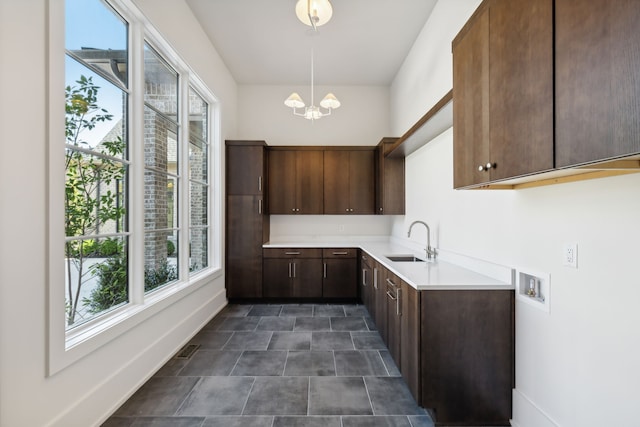 kitchen featuring a notable chandelier, dark brown cabinetry, sink, and hanging light fixtures