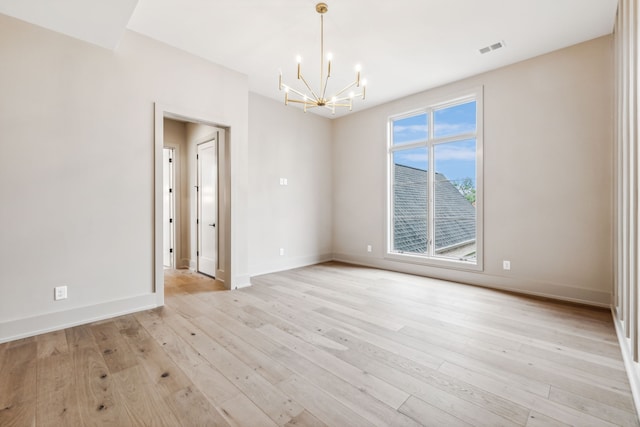 spare room featuring light hardwood / wood-style floors and an inviting chandelier