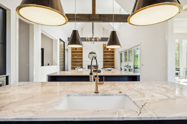 kitchen featuring light stone countertops, sink, a kitchen island, and beamed ceiling