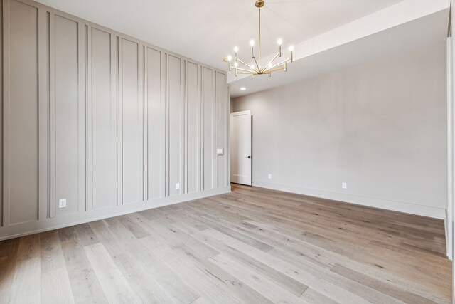 unfurnished room with light hardwood / wood-style flooring and an inviting chandelier