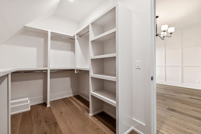 walk in closet featuring hardwood / wood-style flooring and a notable chandelier