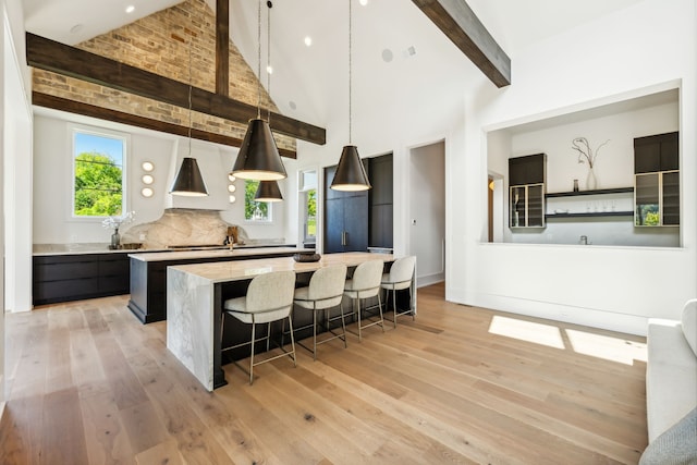 kitchen with decorative light fixtures, high vaulted ceiling, light hardwood / wood-style flooring, beamed ceiling, and a kitchen island