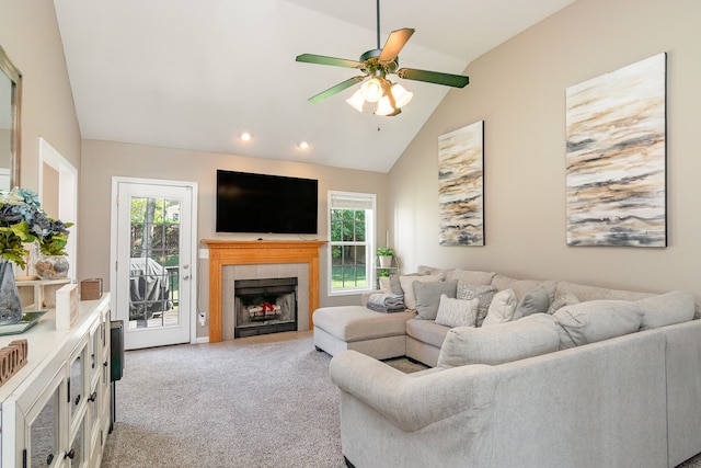 carpeted living room with ceiling fan, high vaulted ceiling, and a tiled fireplace