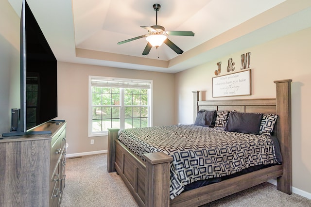 bedroom featuring ceiling fan, a tray ceiling, and light colored carpet