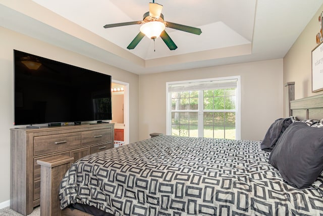 carpeted bedroom featuring ceiling fan and a raised ceiling