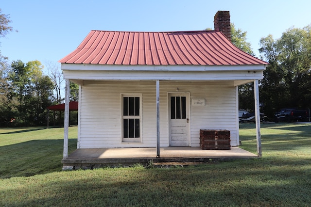 back of property featuring a yard and an outdoor structure