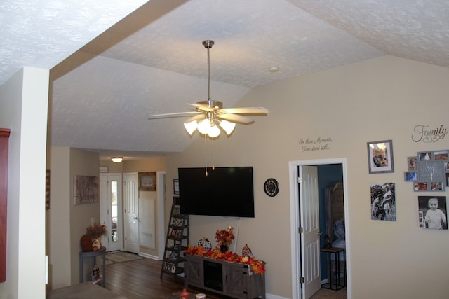 living room with a textured ceiling, lofted ceiling, dark hardwood / wood-style floors, and ceiling fan