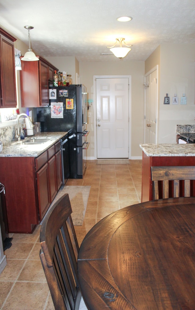 kitchen with dishwasher, sink, light tile patterned floors, decorative light fixtures, and light stone countertops