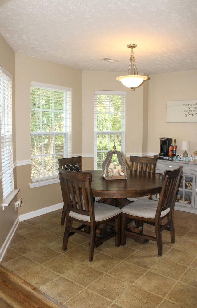 tiled dining room featuring a textured ceiling