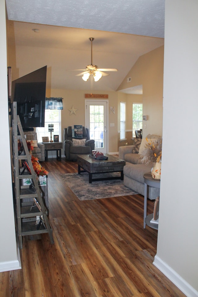 living room with ceiling fan, vaulted ceiling, a textured ceiling, and dark wood-type flooring