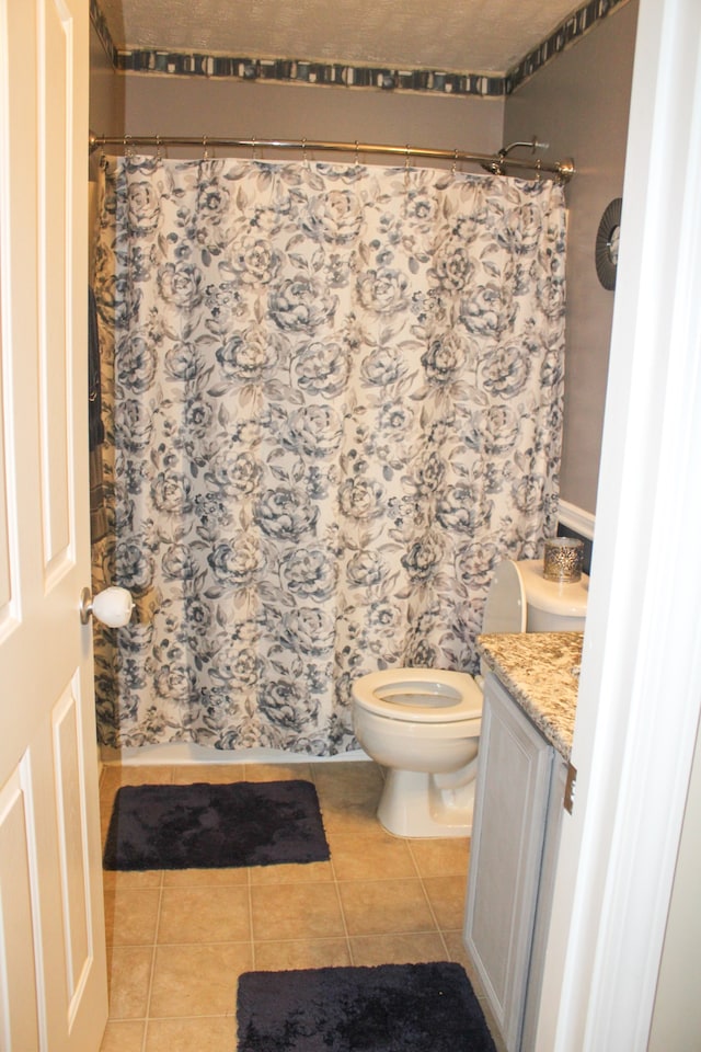 bathroom with a shower with shower curtain, vanity, toilet, and tile patterned floors