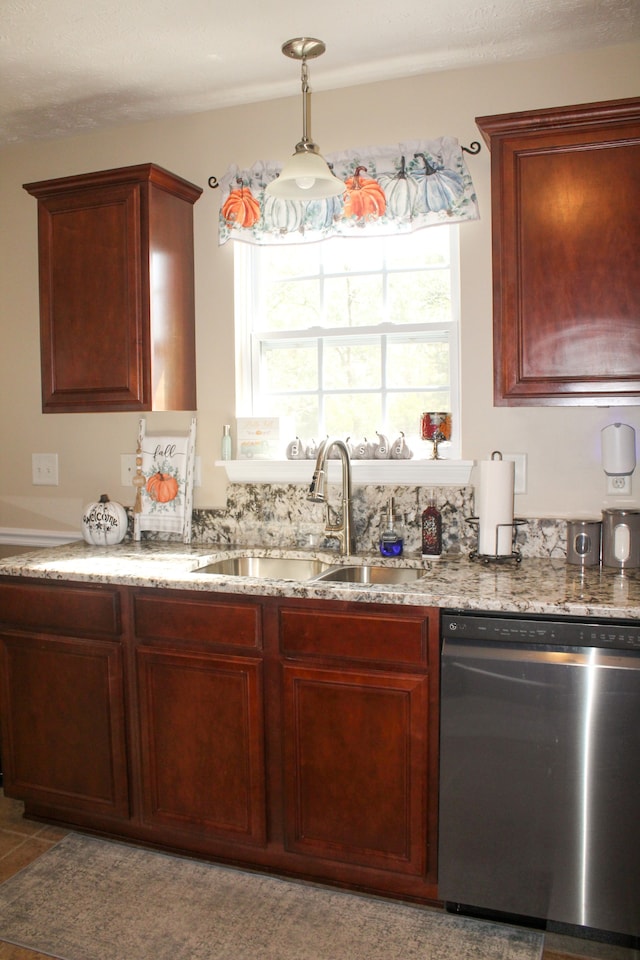 kitchen featuring light stone counters, sink, decorative light fixtures, and stainless steel dishwasher