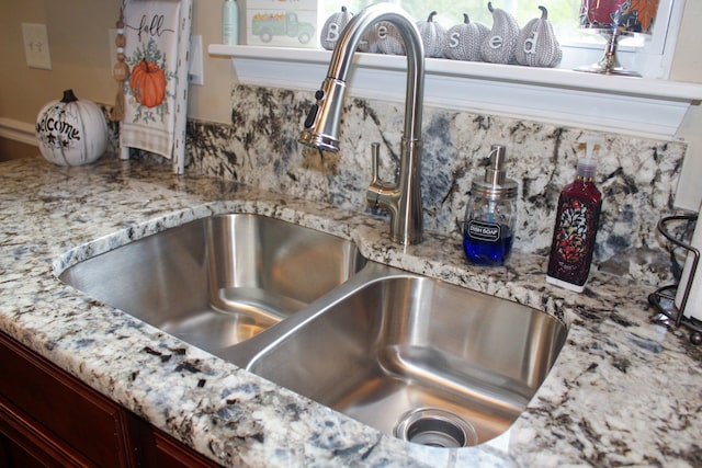 interior details with light stone counters, sink, and decorative backsplash