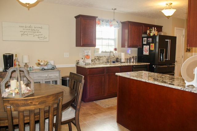 kitchen featuring a textured ceiling, sink, decorative light fixtures, light stone countertops, and black refrigerator with ice dispenser