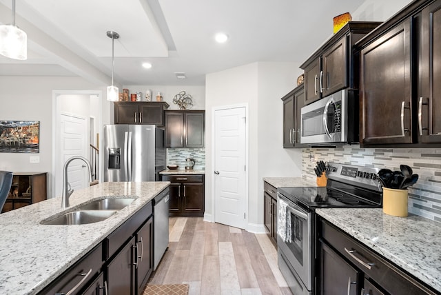 kitchen featuring stainless steel appliances, tasteful backsplash, sink, light hardwood / wood-style floors, and hanging light fixtures