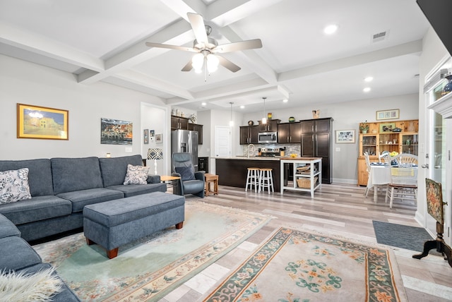 living room with ceiling fan, beamed ceiling, sink, coffered ceiling, and light hardwood / wood-style floors