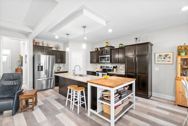 kitchen featuring appliances with stainless steel finishes, dark brown cabinetry, sink, and light hardwood / wood-style floors