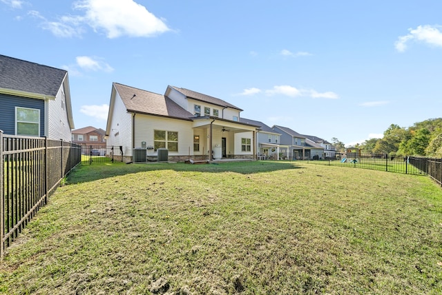 rear view of property featuring central AC unit, a lawn, and a patio area