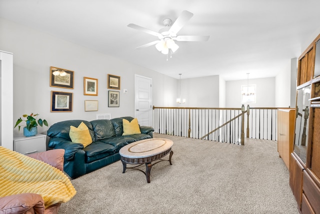 carpeted living room featuring ceiling fan with notable chandelier