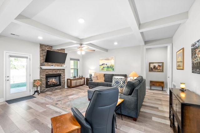 living room featuring ceiling fan, a fireplace, beam ceiling, and light hardwood / wood-style floors