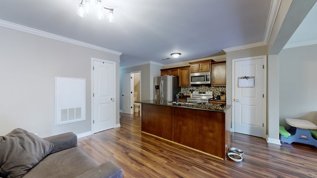 kitchen with ornamental molding, tasteful backsplash, stainless steel appliances, dark hardwood / wood-style floors, and dark stone counters