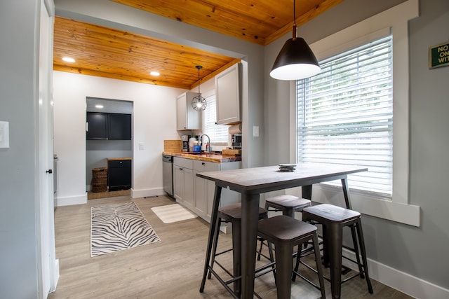 dining space with light wood-type flooring, wood ceiling, sink, and a wealth of natural light