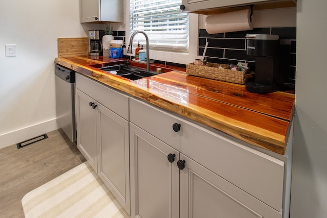 kitchen featuring light wood-type flooring, dishwasher, wood counters, and sink