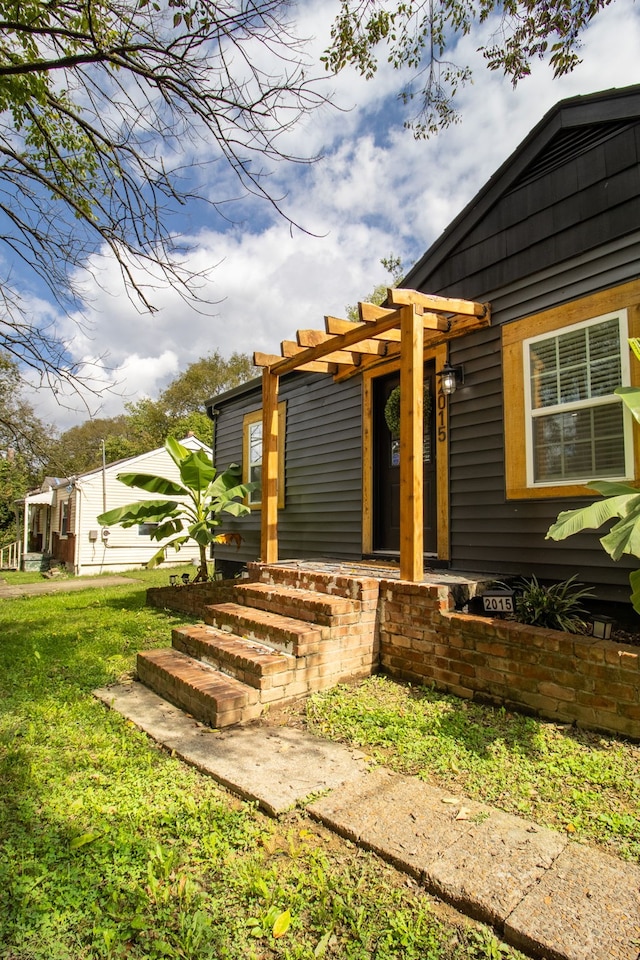 entrance to property featuring a lawn and a pergola