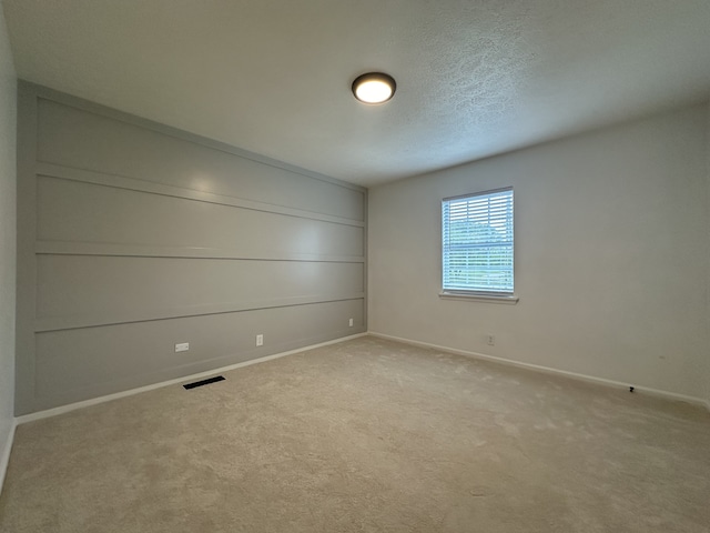 empty room featuring a textured ceiling and light colored carpet