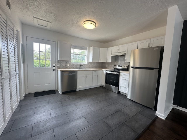 kitchen featuring decorative backsplash, white cabinetry, a textured ceiling, and appliances with stainless steel finishes