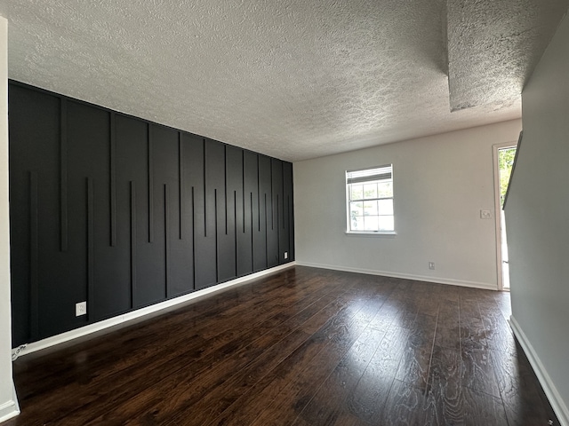 spare room featuring a textured ceiling and dark hardwood / wood-style floors