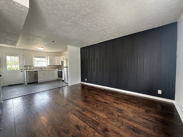 unfurnished living room featuring a textured ceiling and dark hardwood / wood-style flooring