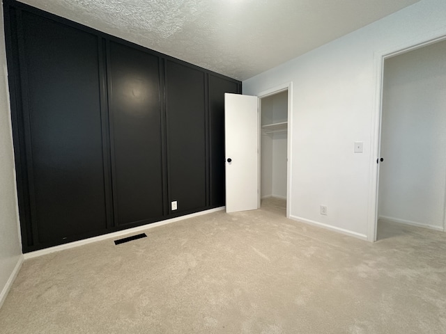 unfurnished bedroom with a textured ceiling, light colored carpet, and a closet