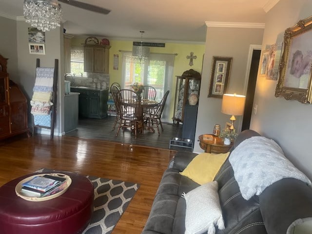 living room featuring ornamental molding, ceiling fan with notable chandelier, and dark hardwood / wood-style flooring