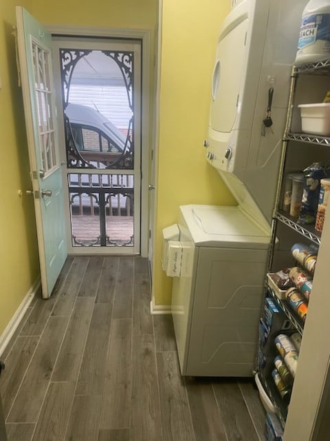 washroom with dark hardwood / wood-style floors and stacked washer and clothes dryer