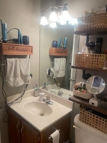 bathroom featuring toilet, an inviting chandelier, and vanity