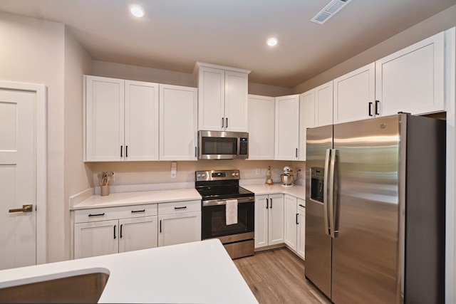 kitchen with appliances with stainless steel finishes, light hardwood / wood-style floors, and white cabinetry