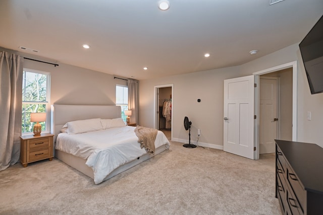 bedroom featuring a spacious closet, a closet, and light carpet