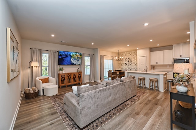 living room featuring light wood-type flooring, sink, and a chandelier