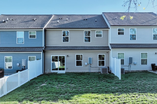 back of house with central air condition unit and a yard