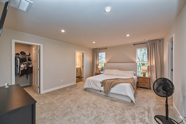 carpeted bedroom featuring a spacious closet, a closet, ensuite bath, and multiple windows