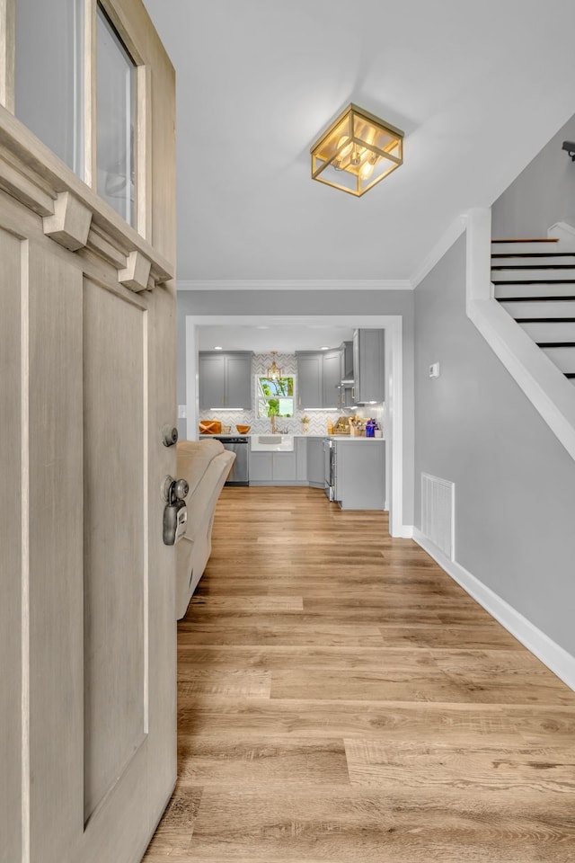 foyer featuring light wood-type flooring and crown molding