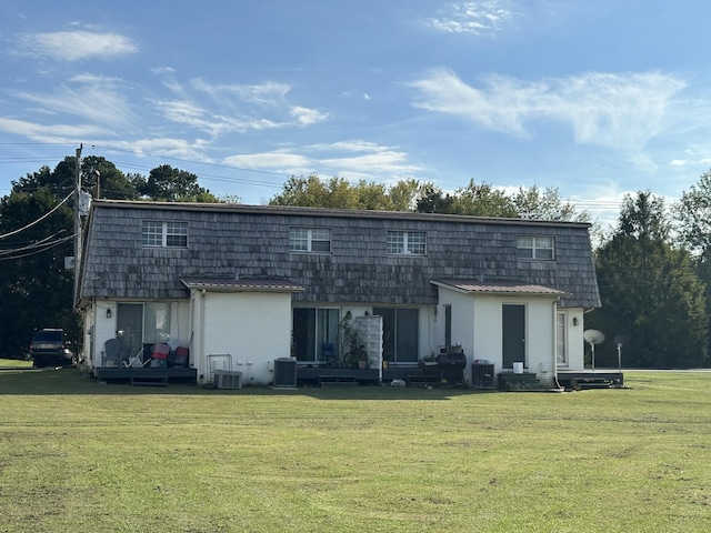 rear view of property featuring cooling unit and a yard