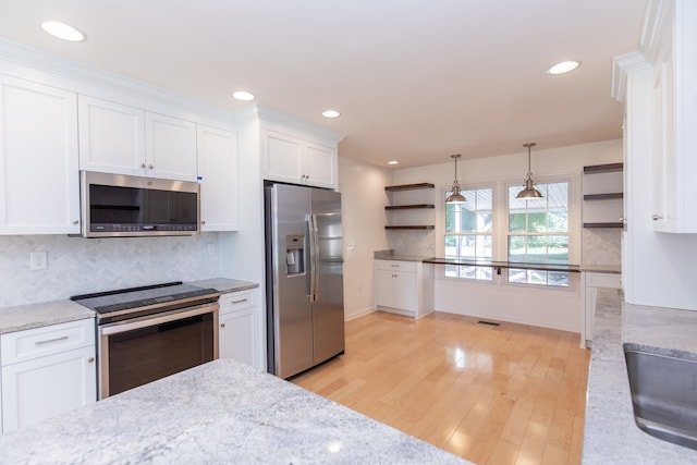 kitchen featuring light stone counters, light hardwood / wood-style floors, white cabinetry, appliances with stainless steel finishes, and decorative light fixtures