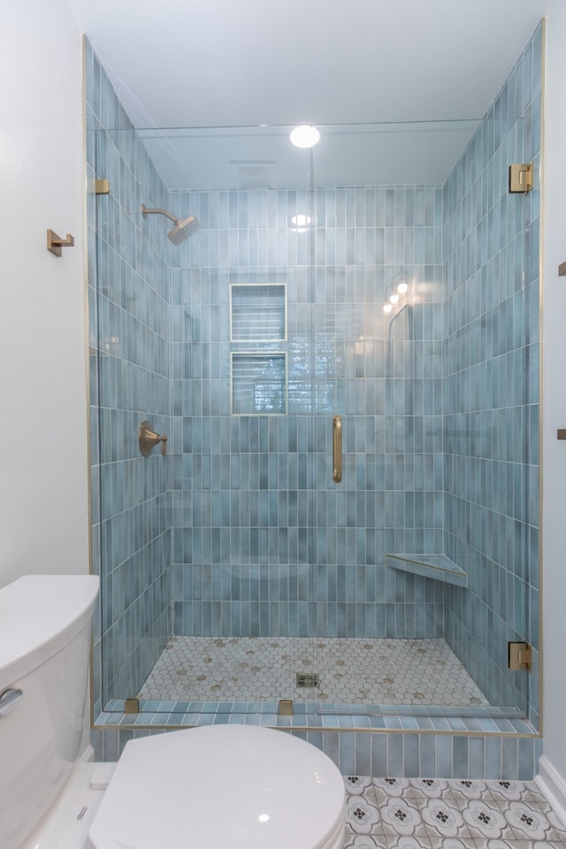 bathroom with tile patterned flooring, a shower with shower door, and toilet