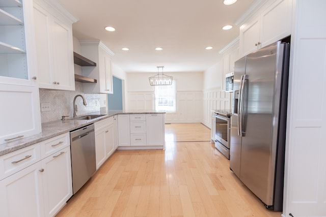 kitchen with appliances with stainless steel finishes, white cabinetry, sink, and light hardwood / wood-style flooring