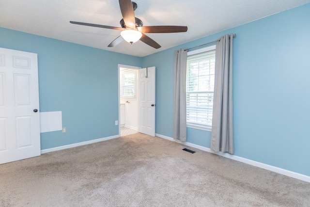 spare room featuring a textured ceiling, ceiling fan, and light carpet